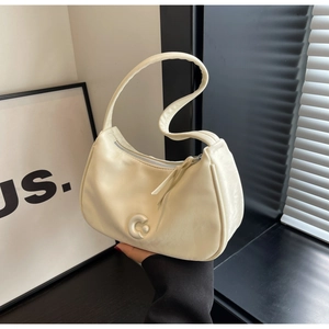 Détail du sac hobo beige avec pompon en cuir et décoration du logo C métallique élégant