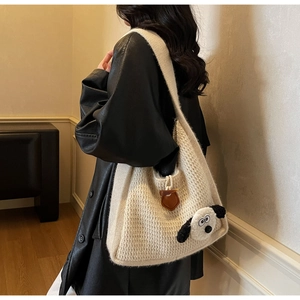 Detail of a beige knit tote bag featuring a cute 3D puppy doll and a brown leather tag
