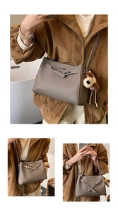 Detail of grey pebble leather handbag featuring metal turn-lock and plush puppy keychain