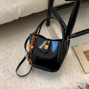 Détail du sac seau noir avec fermoir doré et breloque décorative en perles de bois