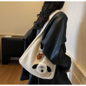 Close-up of beige knitted tote bag featuring a cute cartoon plush character and leather strap