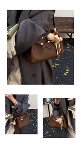 Detail of a dark brown leather bucket bag with silver hardware lock and cute puppy charm
