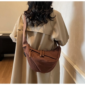 Detail of brown nylon crescent bag with woven zipper and adjustable shoulder strap