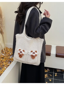 Detail of cute panda plush decor on beige knitted tote bag with textured knit pattern