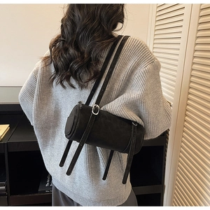 Detail of minimalist black cylindrical shoulder bag with silver buckles on leather straps