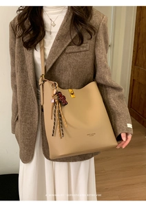 Détail du sac bandoulière rétro en cuir beige avec fermoir doré et ours décoratif