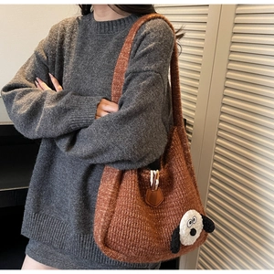 Detail of a brown knit tote bag with a cartoon puppy patch and wooden button closure