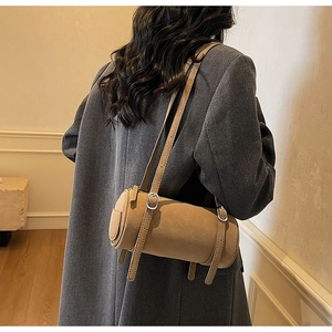 Detail view of khaki leather barrel bag with silver hardware and adjustable shoulder strap