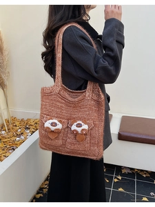 Detailed close-up of brown knit tote bag with 3D cat plush dolls and cozy texture