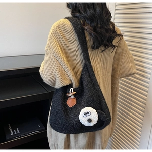 Detail view of black plush shoulder bag with a cute 3D cartoon sheep head ornament