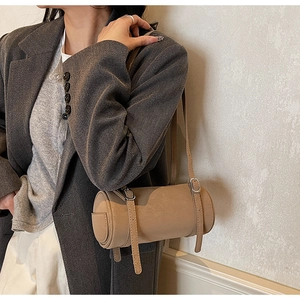 Detail of khaki cylindrical shoulder bag with matte texture and decorative silver buckles