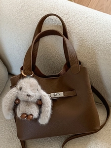 Brown litchi grain leather bucket bag with silver lock and plush rabbit pendant