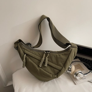 Detail of army green nylon dumpling crossbody bag with woven zipper and wide strap