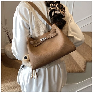 Detail of a brown lychee pattern leather bucket bag with silver buckle on a strap