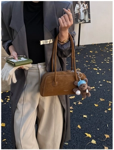 Brown suede shoulder bag with bear pendant and knitted gloves in autumn setting