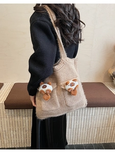 Detail of knitted khaki tote bag with plush cat charms and two large front pockets