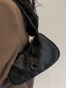 Sac hobo noir à motif marbre avec boucle ronde porté par un mannequin de mode