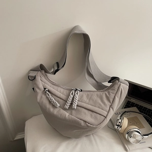 Detail of grey nylon crescent bag showing textured fabric and multiple zipper pulls