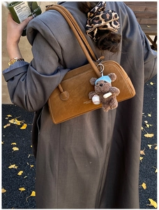 Brown vintage suede underarm bag with teddy bear charm on grey long coat
