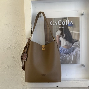 Détail d'un sac seau en cuir marron avec fermoir rotatif en métal et breloque en ours