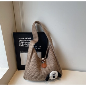 Close-up of knit tote bag with 3D cute cartoon plush ornament and leather strap