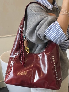 Schultertasche in Burgund mit glänzendem Leder, silbernen Nieten und Quasten-Anhänger