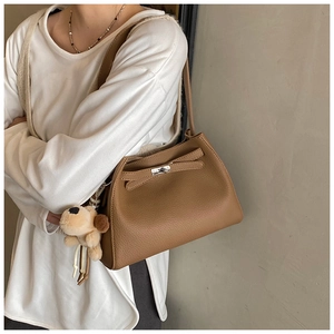 Detail of brown litchi leather bag with silver twist lock and dog plush charm