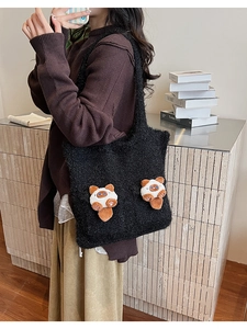 Detail of black plush tote bag featuring cute cartoon cat pendants for winter casual style