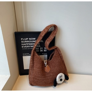 Detail of a brown knit shoulder bag featuring a cute cartoon dog patch and wooden toggle closure