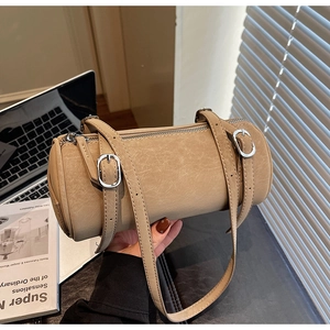 Close-up of beige cylindrical bag with vintage leather texture and silver hardware details