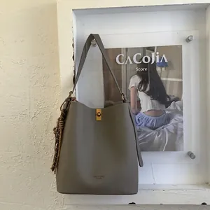 Vue détaillée du sac seau en cuir taupe avec fermoir doré et cordon tressé élégant