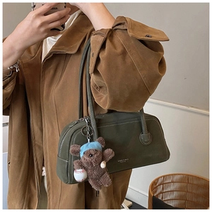 Detail of retro dark green matte underarm bag with a cute plush bear charm accessory
