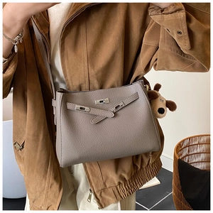 Detail of taupe leather crossbody bag with silver twist lock and plush puppy charm