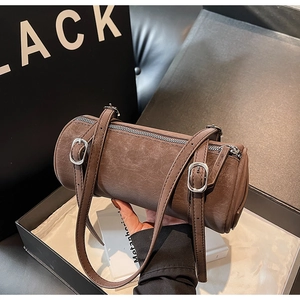Detail of a brown leather barrel bag with silver hardware and dual shoulder straps