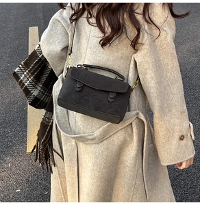 Close-up of a vintage brown matte crossbody bag styled with a warm wool coat