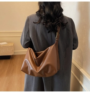 Detail of soft brown leather tote bag with wide adjustable strap on shoulder