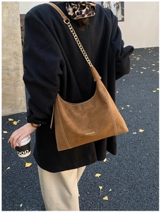 Brown suede hobo bag with contrast stitching and metal chain strap shown on street