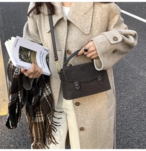 Detail of vintage brown leather handbag styled with a beige tweed coat and magazine