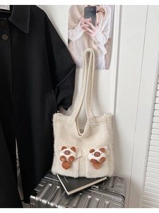 Detail of knitted tote bag showing cat plush ornaments on cream fabric with shoulder strap