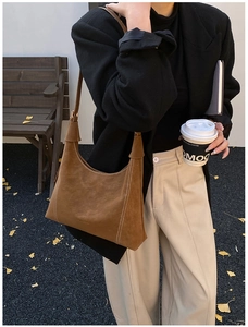 Detail of vintage brown suede shoulder bag with contrast stitching in street scene