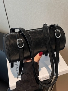Minimalist black cylinder shoulder bag in vintage leather with silver buckle straps