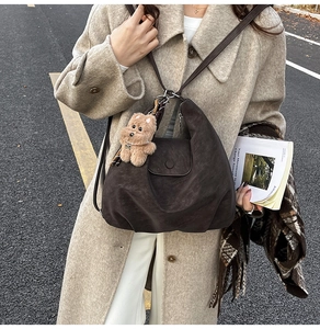Détail du sac hobo en daim marron foncé avec un charmant ours en peluche pour un look automnal