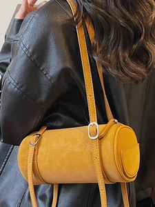 Ginger yellow cylinder shoulder bag in matte faux suede shown on black leather jacket