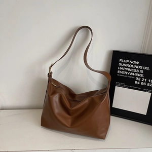 Detail view of the soft brown leather tote bag with adjustable strap and metal hardware