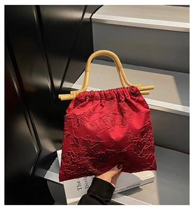 Macro detail of burgundy floral jacquard fabric with bamboo handles and drawstring closure