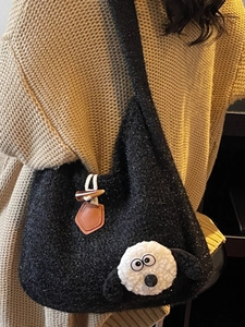 Black plush tote bag with sheep detail and toggle button on a winter knit sweater