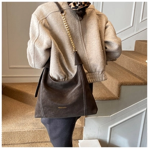 Detail of vintage brown suede tote bag with contrast stitching and gold chain strap