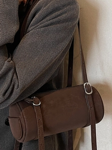 Minimalist dark brown cylinder bucket bag with silver buckle and thin shoulder strap