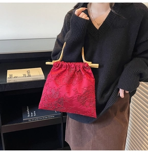 Detail of red jacquard tote bag with floral texture and natural wooden handles