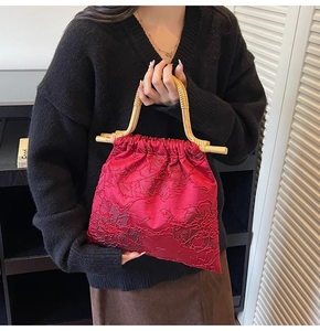 Detail of red satin handbag featuring jacquard patterns and natural bamboo handles